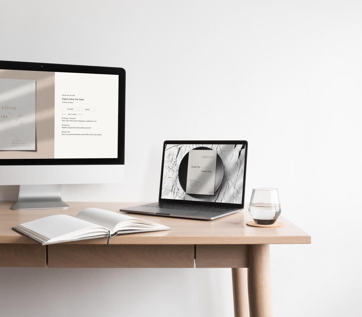 A desk with a computer monitor showing an online save the date card and a laptop screen displaying a black and white online wedding invitation